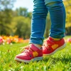 Kinderschuhe, die orthopädische Unterstützung bieten, werden von einem Kind auf Gras getragen.