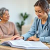 Explore care certificate workbook answers with a caregiver helping a patient in a serene setting.