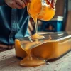 Pouring laminating resin into a mold, showcasing its glossy texture and professional craftsmanship.