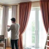 Skilled curtain fitters measuring and preparing curtains in a stylish living room setting.