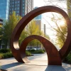 Meticulously crafted acier corten sculpture amidst lush greenery highlighting its unique texture.