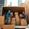 NYC movers expertly handling boxes during a move, showcasing urban energy and professionalism.