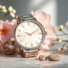 Damen Armbanduhr stilvoll präsentiert auf einer Marmoroberfläche, umgeben von zarten Blumenarrangements.