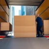 NYC movers efficiently loading furniture into a truck with urban skyline backdrop.